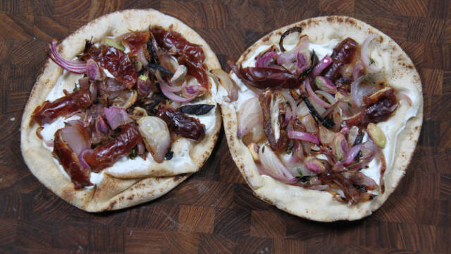 To fladbrødspizzaer på mørkt skærebræt.