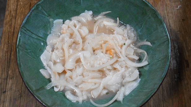Billedet viser en portionsanrettet mexcansk sashimi med citronsaft og løg.