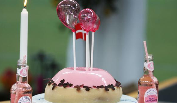 Feminin, lyserød kage med sukkerballoner på toppen