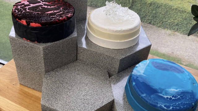 Tre kager der står på hver sin søjle. Den første er blå, den anden hvid og den tredje sort og rød.