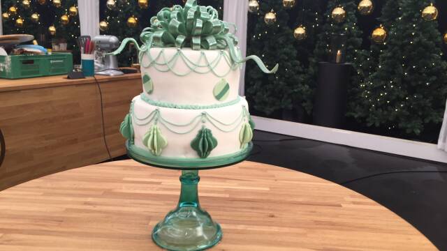 hvid kage med grønt pynt og isomaltsløjfe på toppen