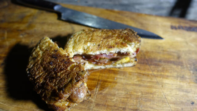 paneret sandwich med bacon og ost på skærebræt